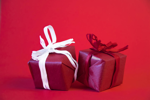 Christmas gifts presents on red background. Simple, classic, red and white wrapped gift boxes with ribbon bows and festive holiday decorations. - Photo, Image
