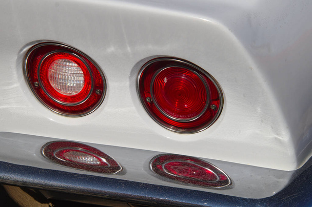 Due fanale posteriore rotondo riflesso dal paraurti posteriore cromato di un'auto classica bianca. - Foto, immagini