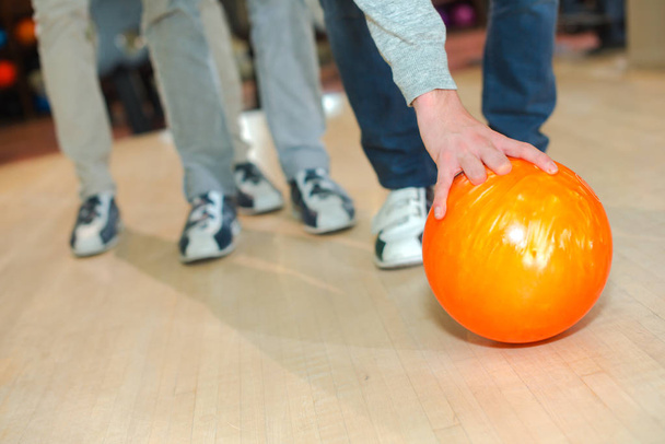 Man leaning down to pick up bowling ball - Photo, Image