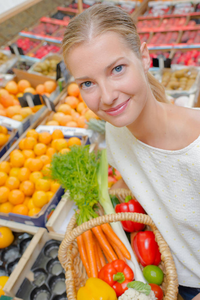 Lady holding wicker basket of vegetables, in supermarket - Φωτογραφία, εικόνα