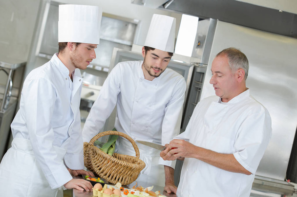 crew of positive professional cooks working at restaurant kitchen - Foto, Bild