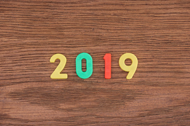 top view of 2019 date made of colorful numbers on wooden background - Fotografie, Obrázek