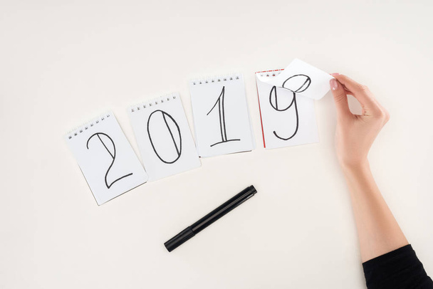 partial view of woman flipping over date written on notes symbolizing change from 2018 to 2019 isolated on white - Foto, Imagem