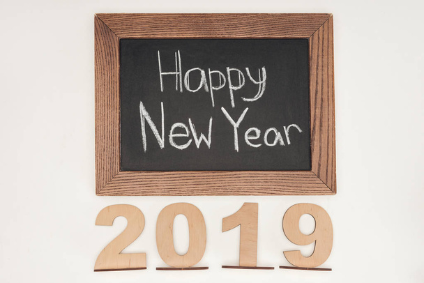 vista superior del texto 'feliz año nuevo' en pizarra con fecha 2019 de madera contrachapada aislada en blanco
 - Foto, Imagen