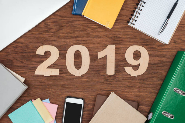 felülnézet fából készült íróasztal, jegyzetfüzet, smartphone és 2019 dátum készült rétegelt lemez - Fotó, kép