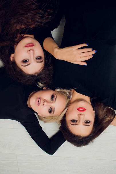 Three girl friends with suckers smiling lie. - 写真・画像
