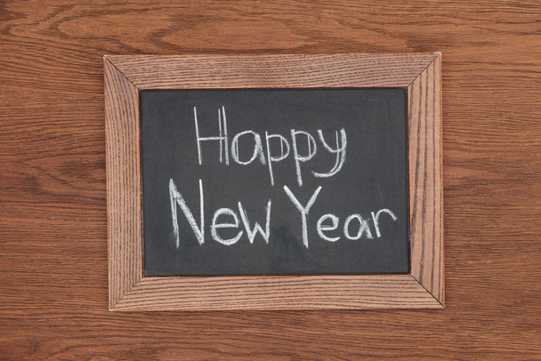 κάτοψη του «ευτυχισμένο το νέο έτος» κείμενο σε πίνακα κιμωλίας με φόντο ξύλινη - Φωτογραφία, εικόνα