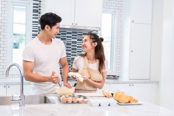 Asiatische Paare kochen und backen gemeinsam in der Küche. Mann und Frau schauen sich zu Hause an. Liebe und Glück Konzept süße Flitterwochen und Valentinstag Thema - Foto, Bild