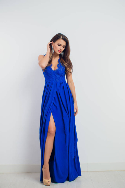 brunette beautiful young woman posing in blue dress. Glamour makeup. Long hair. Studio shot. - Photo, image