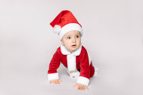 Cute baby wearing santa claus costume on a the floor on white background - Foto, Imagem