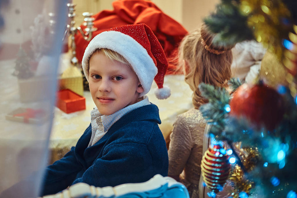 Sister and brother sitting at the table in an elegant living room decorated for Christmas. - 写真・画像