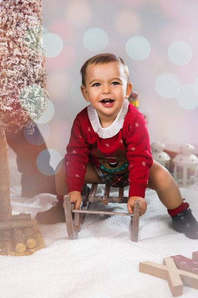 Merry Christmas. Happy little child is wearing a funny Christmas sweater at home. - Foto, afbeelding