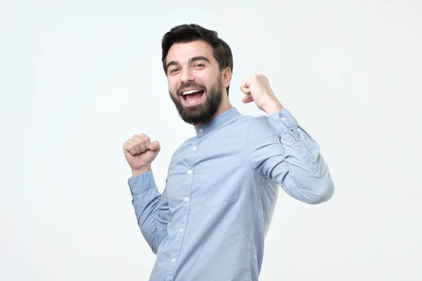 Joven hispano con barba celebra su victoria o éxito, levantando puños
. - Foto, imagen