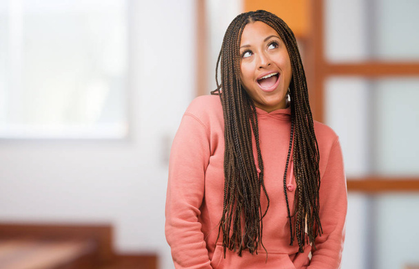 Portret van een jonge zwarte vrouw dragen vlechten opzoeken, denk aan iets leuks en een idee, concept van verbeelding, blij en opgewonden - Foto, afbeelding