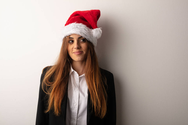 Young business woman wearing santa hat celebrating christmas day - Foto, imagen