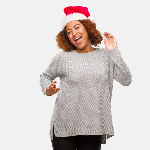 junge schwarze Frau mit Weihnachtsmütze tanzt und hat Spaß - Foto, Bild