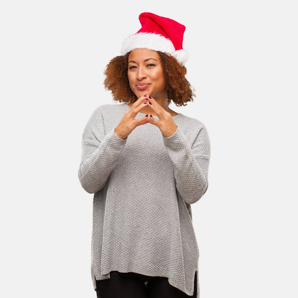 Νεαρή μαύρη γυναίκα που φοράει ένα καπέλο santa επινόηση ενός σχεδίου - Φωτογραφία, εικόνα