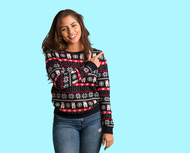 全身若い女性の笑顔と側を指しているクリスマスのジャージを着て - 写真・画像