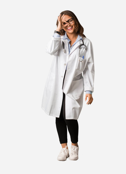 Full body young doctor woman confident doing ok gesture on eye - Foto, afbeelding