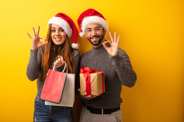 Couple or friends holding gifts and shopping bags cheerful and confident doing ok gesture - Photo, Image