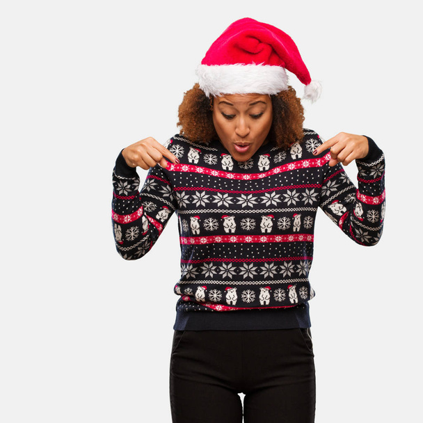 Jovem mulher negra em uma camisola de Natal na moda com impressão apontando para baixo
 - Foto, Imagem