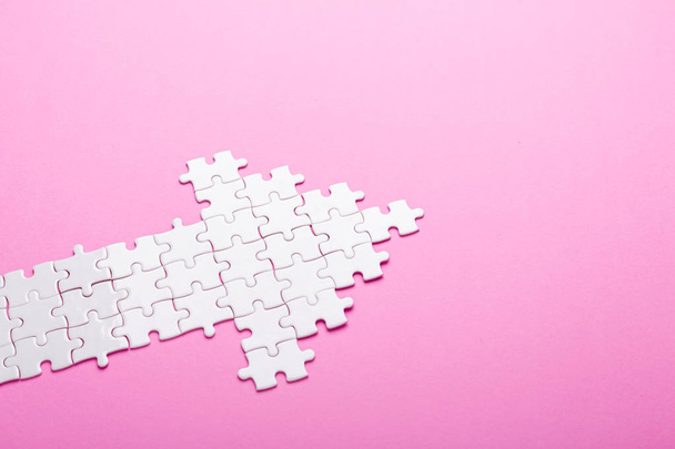 White puzzle. Arrow shape puzzle on pink background. Top view - Photo, image