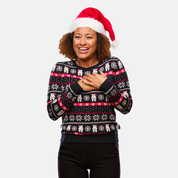 junge schwarze Frau in einem trendigen Weihnachtspullover mit Print macht eine romantische Geste - Foto, Bild