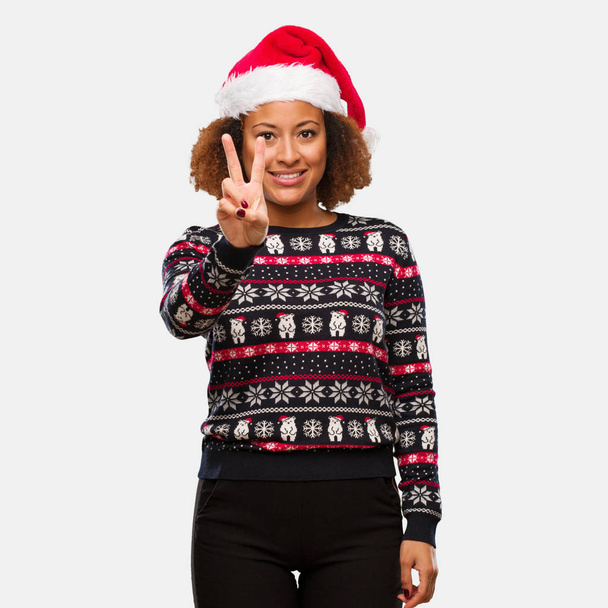 Young black woman in a trendy christmas sweater with print showing number two - Photo, Image