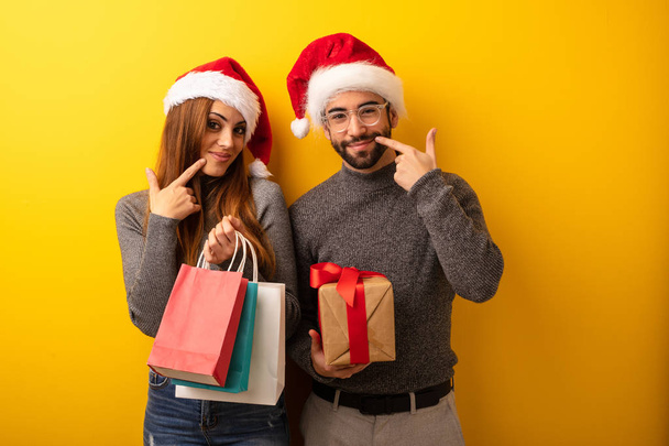 Couple ou amis tenant des cadeaux et des sacs à provisions sourit, pointant la bouche
 - Photo, image