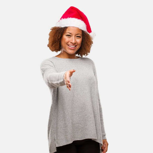 junge schwarze Frau mit Weihnachtsmütze, die sich ausstreckt, um jemanden zu begrüßen - Foto, Bild