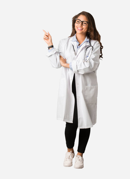 Mujer doctora joven de cuerpo completo apuntando hacia un lado con el dedo
 - Foto, imagen