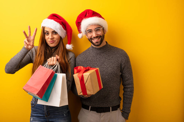 Couple or friends holding gifts and shopping bags showing number three - Foto, afbeelding