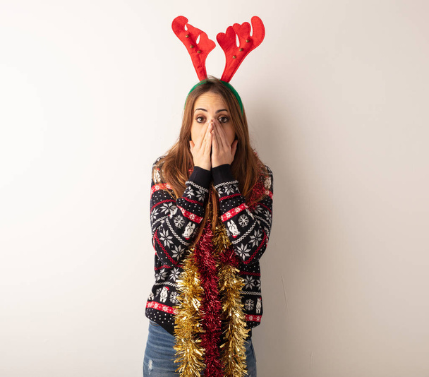 Young pretty woman wearing christmas clothes very scared and afraid hidden - Photo, Image