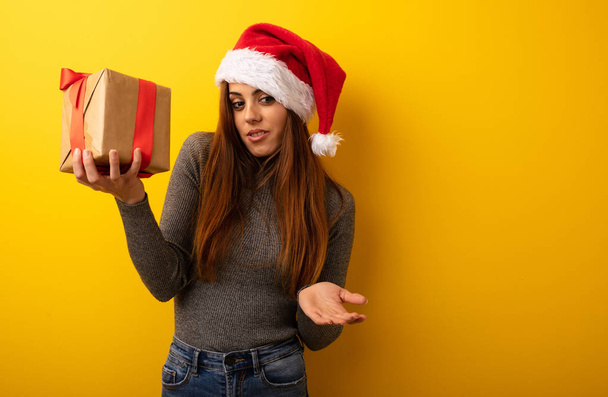 Young pretty woman holding gift confused and doubtful - Photo, Image