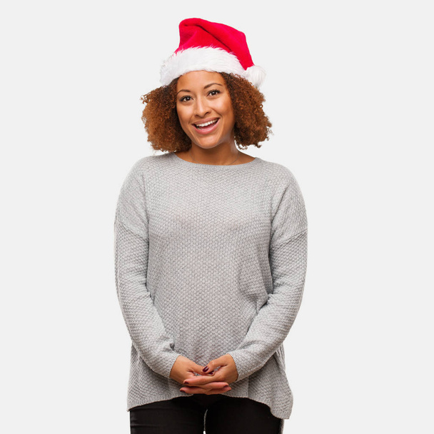 Νεαρή μαύρη γυναίκα που φοράει ένα καπέλο santa χαρούμενα με ένα μεγάλο χαμόγελο - Φωτογραφία, εικόνα