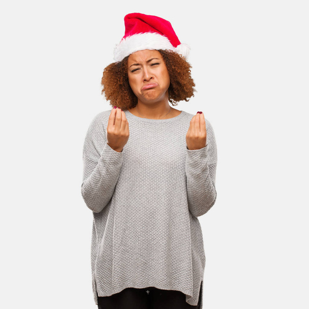junge schwarze Frau mit Weihnachtsmütze, die eine Geste der Not macht - Foto, Bild