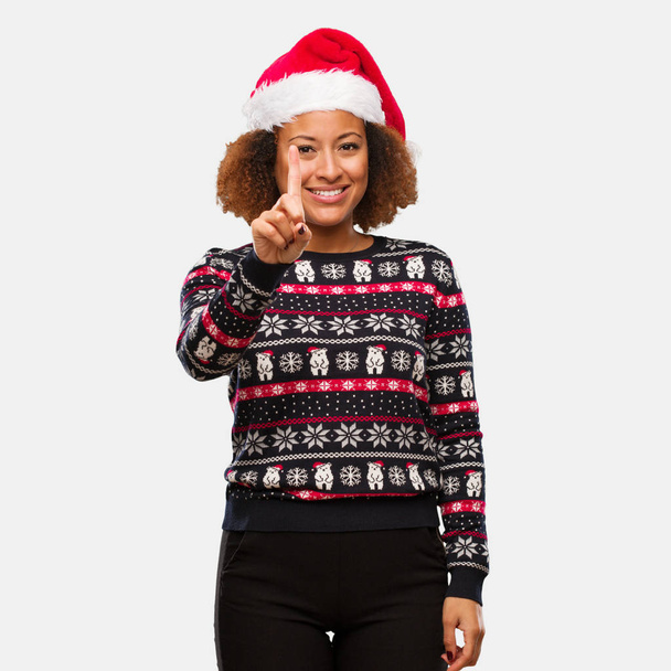 junge schwarze Frau in einem trendigen Weihnachtspullover mit Print, der die Nummer eins zeigt - Foto, Bild