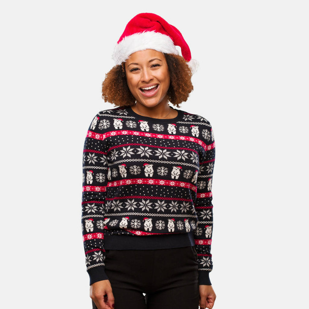 Νεαρή μαύρη γυναίκα σε ένα καθιερώνον τη μόδα Χριστούγεννα πουλόβερ με print χαρούμενα με ένα μεγάλο χαμόγελο - Φωτογραφία, εικόνα