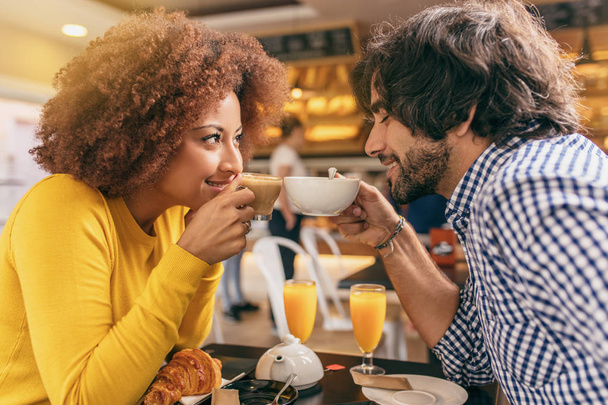 カフェで朝食を持っている若いカップル、飲むお茶とコーヒー、お互いを見ている恋に非常に幸せで快適です. - 写真・画像