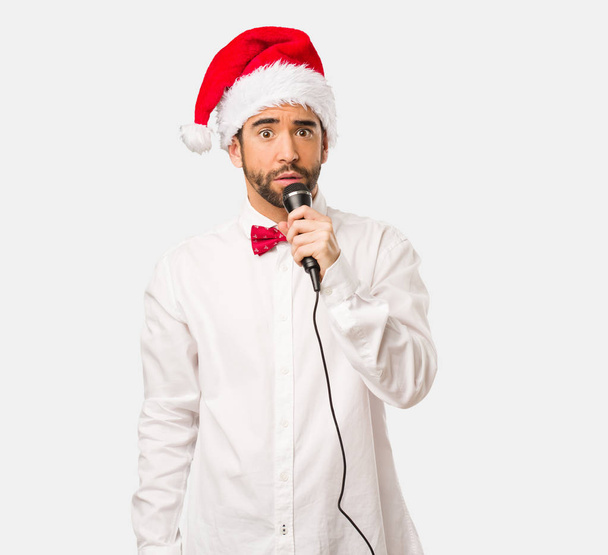 Ο άνθρωπος με το καπέλο το νέο έτος, ένα τραγούδι με ένα μικρόφωνο - Φωτογραφία, εικόνα