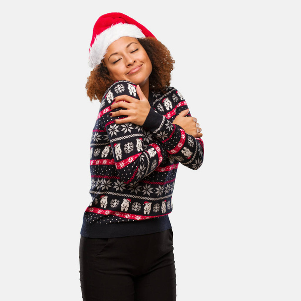 Mujer negra joven en un suéter de Navidad de moda con estampado dando un abrazo
 - Foto, Imagen