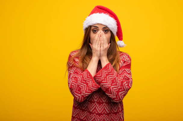 Young woman wearing santa hat very scared and afraid hidden - Photo, Image