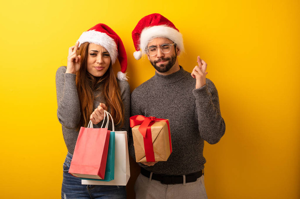 Couple ou amis tenant des cadeaux et des sacs à provisions croisant les doigts pour avoir de la chance
 - Photo, image