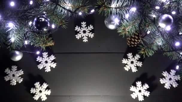 Μαύρο ξύλινο χριστουγεννιάτικο φόντο. Κανόνισε με κλάδους πεύκων στην κορυφή, με φώτα, νέο έτος παιχνίδια, νιφάδες χιονιού. Χώρο για το κείμενο. Το Top view. Γυρίστηκε σε ανάλυση 4 k - Πλάνα, βίντεο