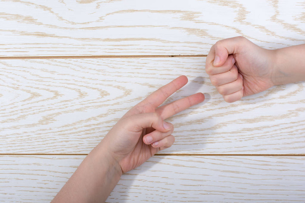 Hands making rock, paper, scissors gesture on a wooden background - Photo, Image