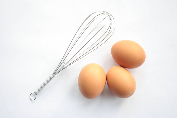 Whisk and eggs on white background - Foto, Imagem