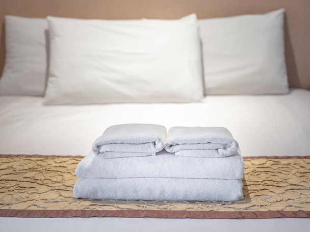 Toalhas brancas limpas e três travesseiros brancos na cama em quarto de luxo no hotel
. - Foto, Imagem