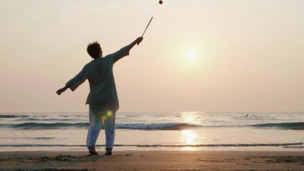 スローモーションでビーチで太極拳気球ボールを弾いてアクティブ シニア カップル. - 映像、動画