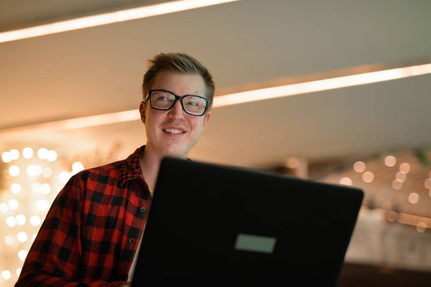 Νέοι ευτυχισμένη Hipster άνθρωπος σκέφτεται ενώ χρησιμοποιείτε φορητό υπολογιστή στην ύπαιθρο το βράδυ - Φωτογραφία, εικόνα