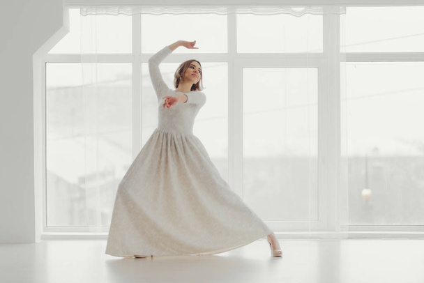 The girl in white is dancing on the background of large windows - Foto, immagini